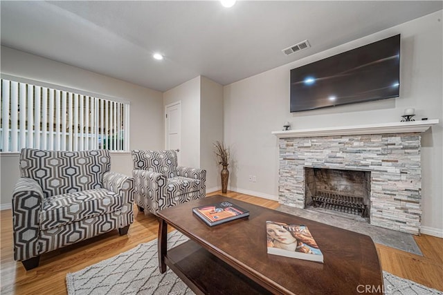 living area with baseboards, visible vents, wood finished floors, a fireplace, and recessed lighting