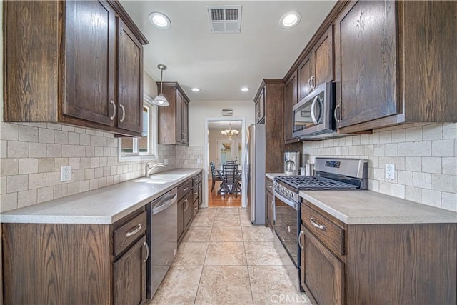 kitchen with appliances with stainless steel finishes, visible vents, a sink, and dark brown cabinetry