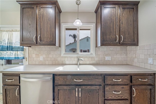 kitchen featuring light countertops, stainless steel dishwasher, a sink, and dark brown cabinetry