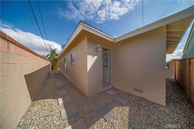 view of side of home featuring crawl space, a fenced backyard, and stucco siding