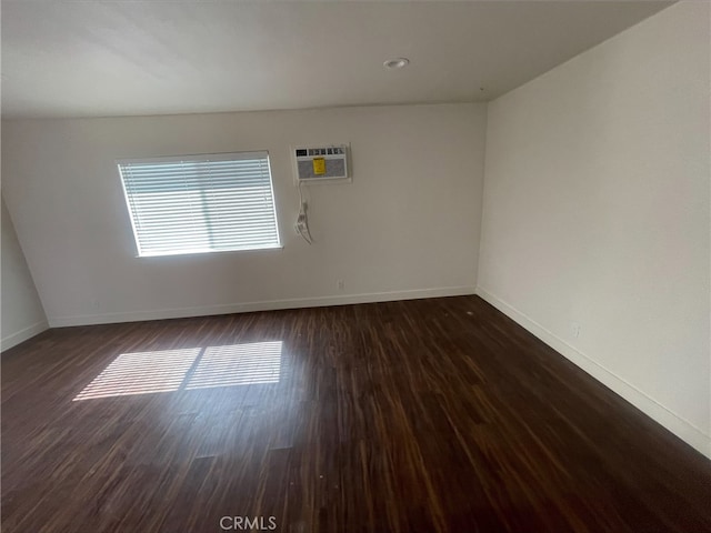 unfurnished room featuring dark wood finished floors, baseboards, and a wall mounted AC