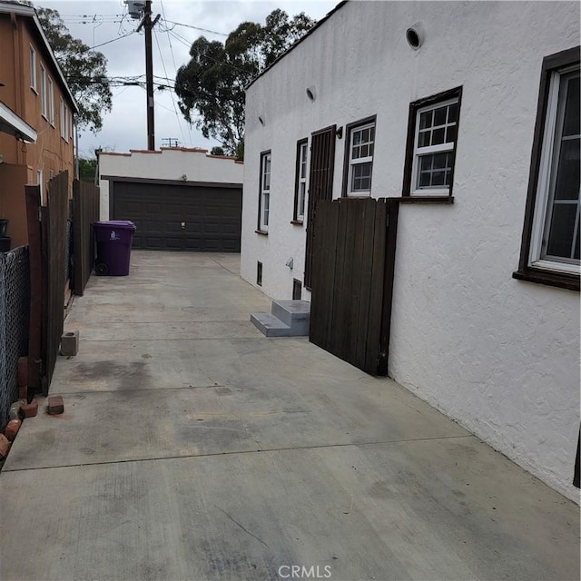 view of side of home featuring entry steps, fence, an outdoor structure, and stucco siding