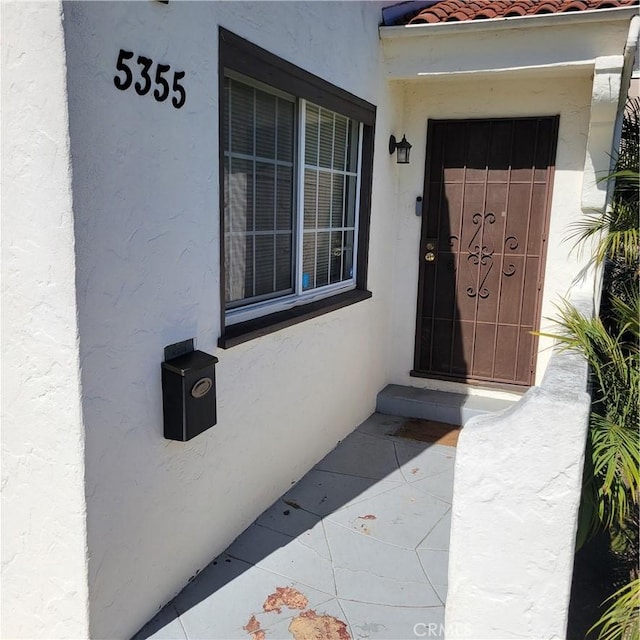 property entrance with stucco siding and a tiled roof