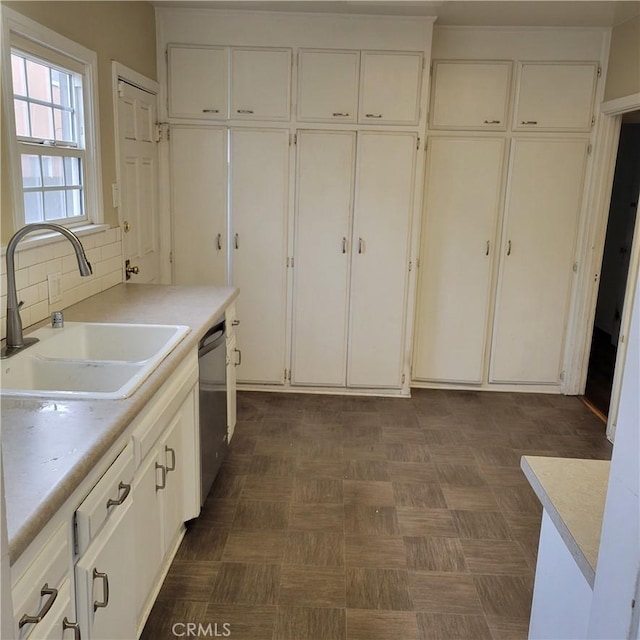 kitchen featuring white cabinets, a sink, backsplash, and stainless steel dishwasher