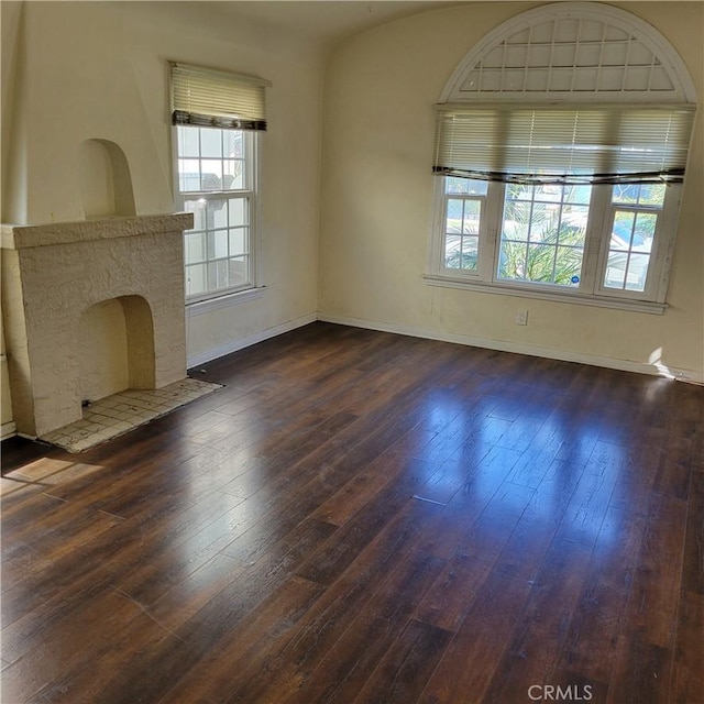 unfurnished living room featuring dark wood-type flooring, a fireplace, and baseboards