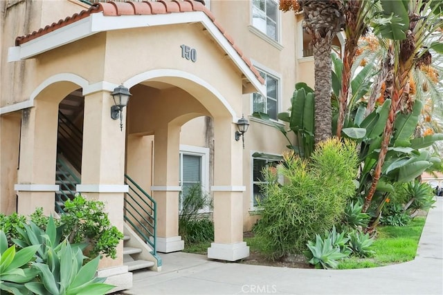 entrance to property featuring a tile roof and stucco siding