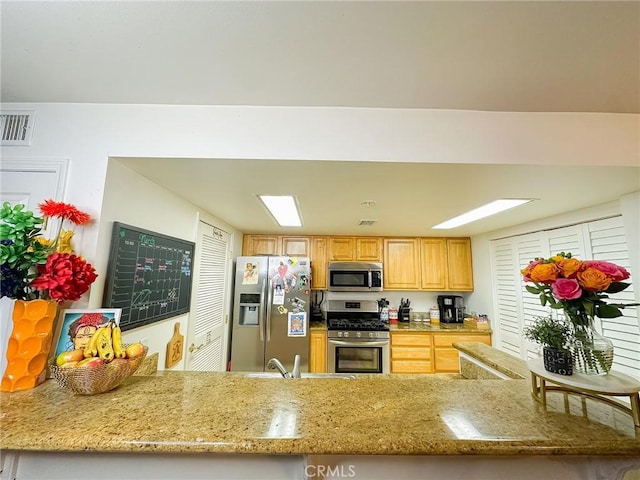 kitchen with stainless steel appliances, light stone counters, and visible vents