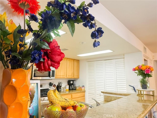 kitchen with light brown cabinets, stainless steel microwave, and light countertops