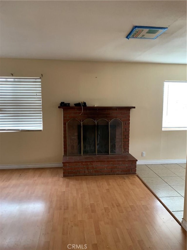 unfurnished living room featuring a fireplace, light wood-style flooring, and baseboards