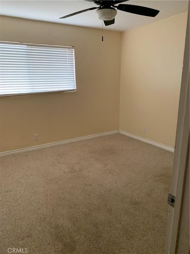 carpeted spare room with a ceiling fan and baseboards