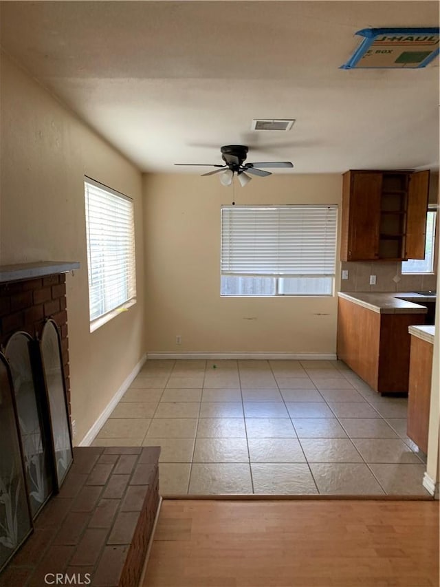 kitchen featuring brown cabinets, a fireplace, open shelves, visible vents, and a ceiling fan