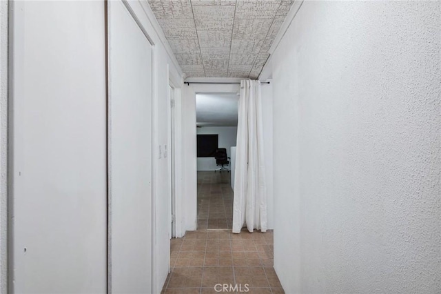 hallway with tile patterned flooring and a textured wall