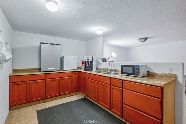 kitchen featuring light countertops, a sink, and a textured ceiling