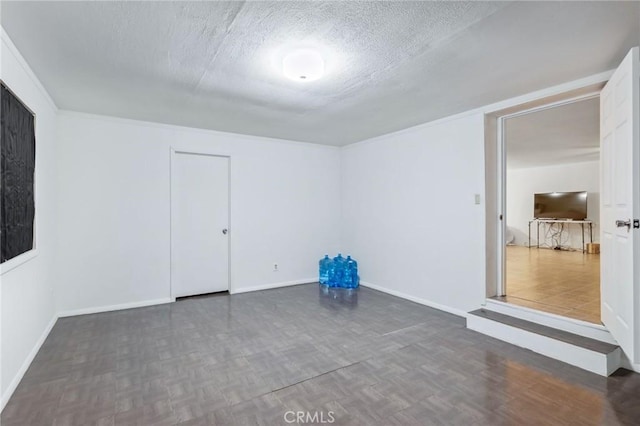 spare room with a textured ceiling, parquet floors, and baseboards