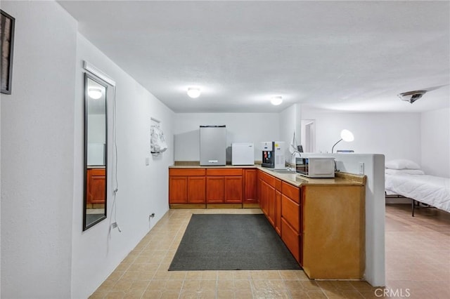 kitchen with open floor plan, a peninsula, stainless steel microwave, and light countertops