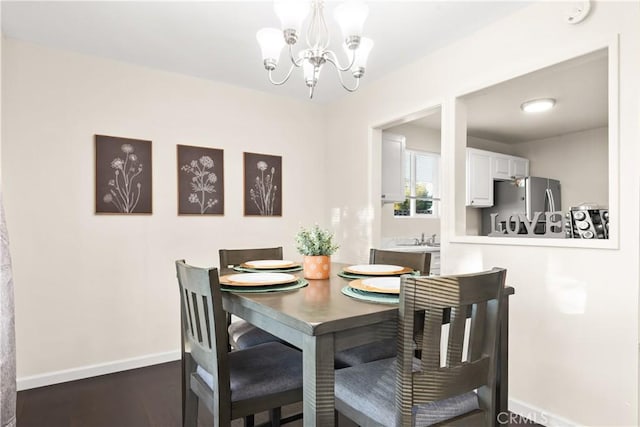 dining space featuring a chandelier, dark wood finished floors, and baseboards