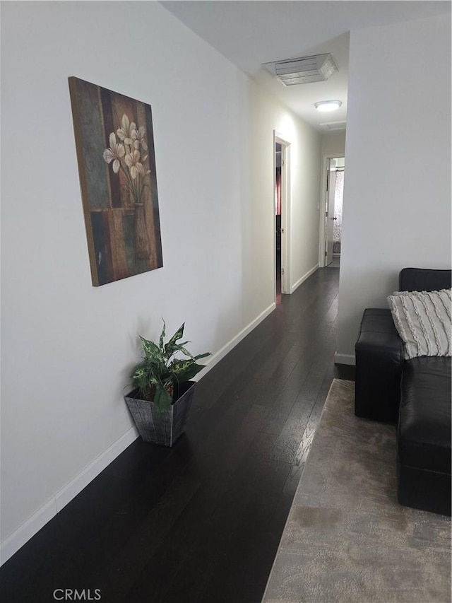 hall featuring baseboards, visible vents, and hardwood / wood-style floors