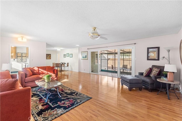 living room with a textured ceiling, a ceiling fan, and wood finished floors