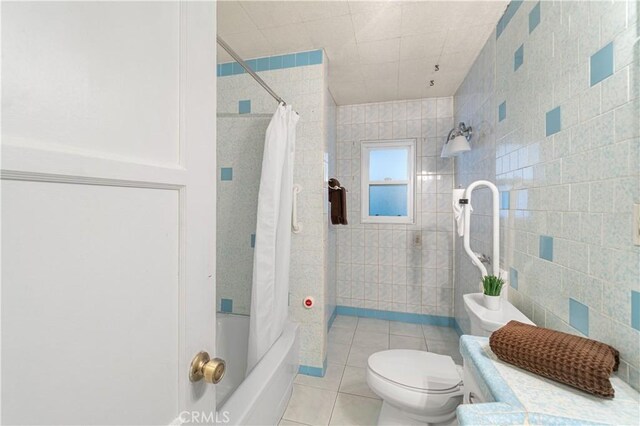 full bathroom featuring toilet, shower / tub combo with curtain, tile walls, and tile patterned floors