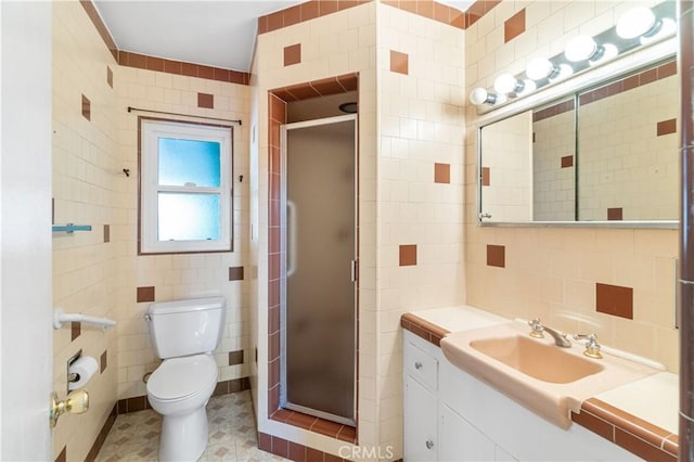 bathroom with a stall shower, toilet, tile walls, and vanity