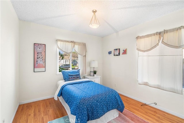 bedroom featuring a textured ceiling, wood finished floors, and baseboards