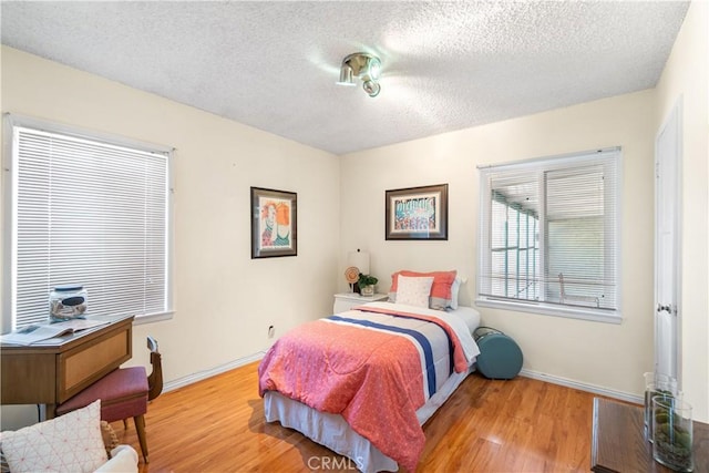 bedroom featuring a textured ceiling, baseboards, and wood finished floors