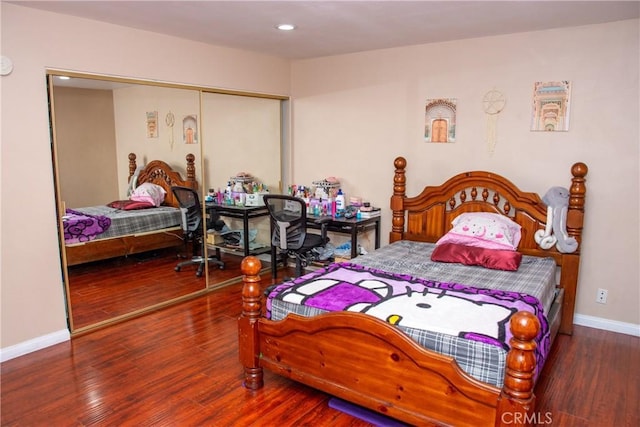 bedroom with a closet, recessed lighting, wood finished floors, and baseboards