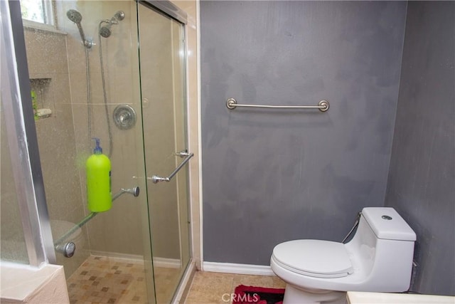 full bath featuring baseboards, a shower stall, toilet, and tile patterned floors