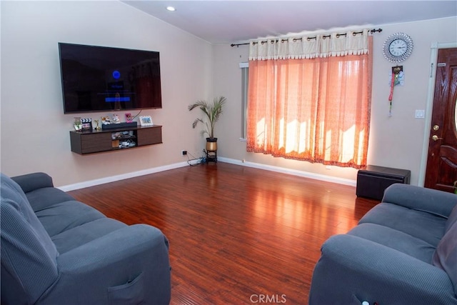 living area featuring vaulted ceiling, wood finished floors, and baseboards