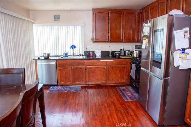 kitchen featuring dark countertops, brown cabinetry, stainless steel appliances, and dark wood-type flooring