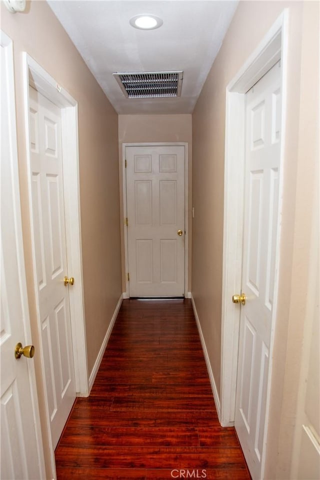 corridor featuring dark wood-style floors, baseboards, and visible vents