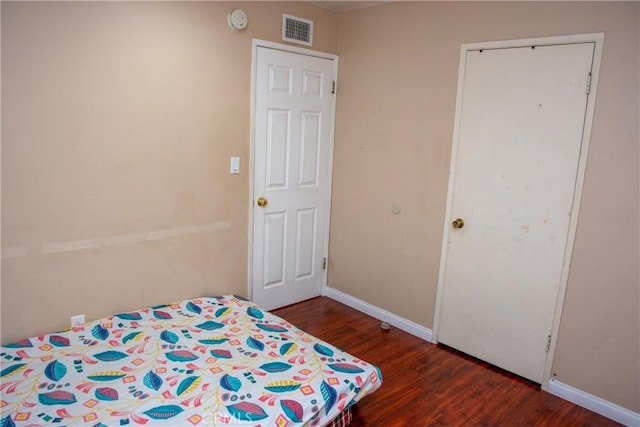 unfurnished bedroom featuring baseboards, visible vents, and wood finished floors