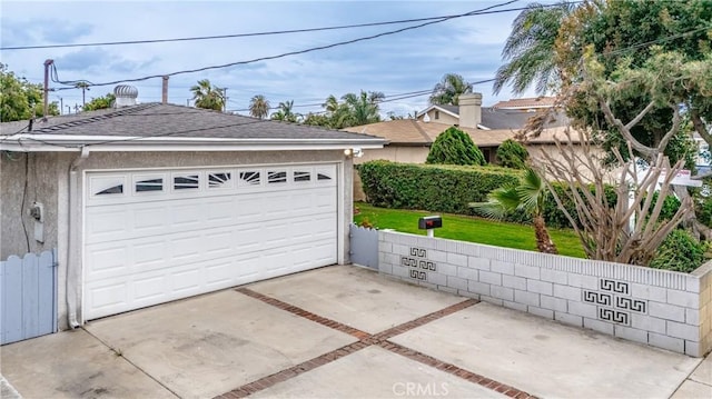 garage featuring driveway and fence