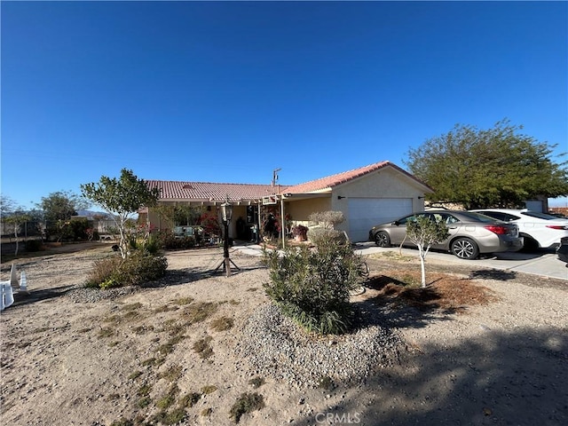 single story home featuring an attached garage, driveway, a tiled roof, and stucco siding