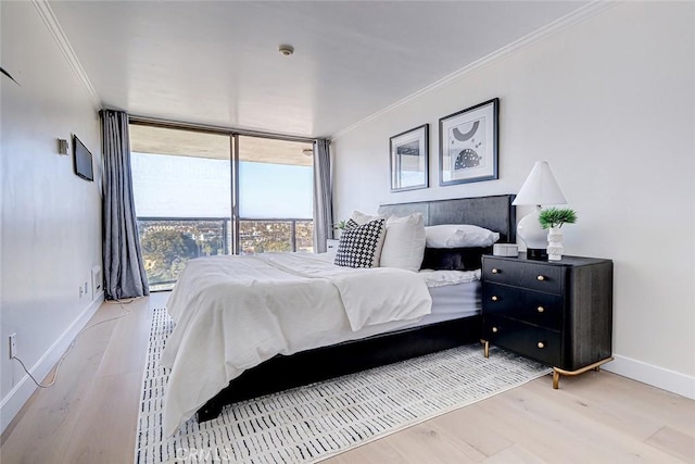 bedroom with baseboards, floor to ceiling windows, crown molding, and wood finished floors