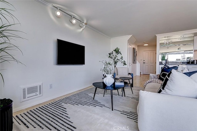 living room featuring baseboards, rail lighting, and crown molding