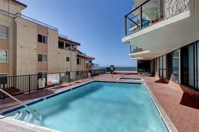 community pool with fence, a community hot tub, and a patio