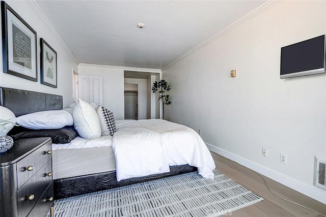 bedroom with crown molding, baseboards, and wood finished floors