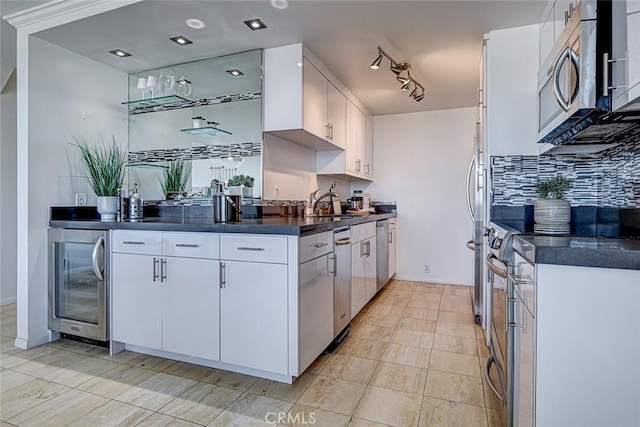 kitchen with wine cooler, stainless steel appliances, dark countertops, backsplash, and white cabinetry