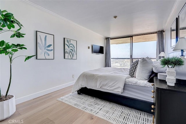 bedroom featuring baseboards, light wood-style flooring, and crown molding