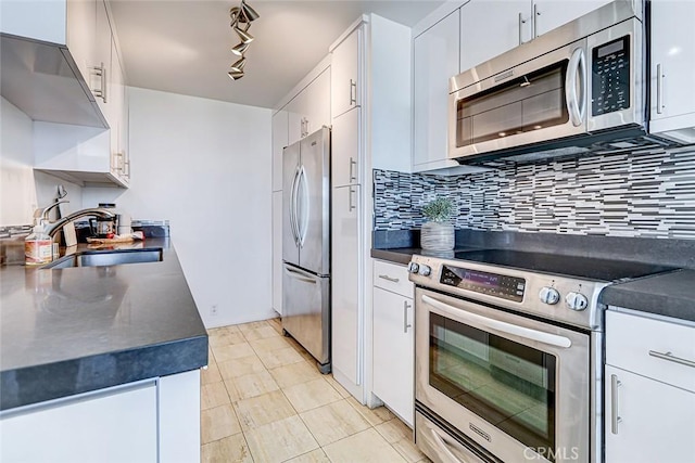 kitchen featuring stainless steel appliances, a sink, white cabinets, decorative backsplash, and dark countertops