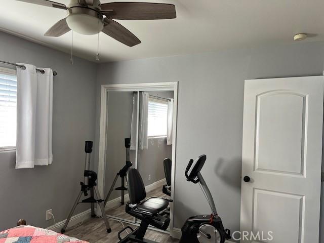 workout room with baseboards and a ceiling fan