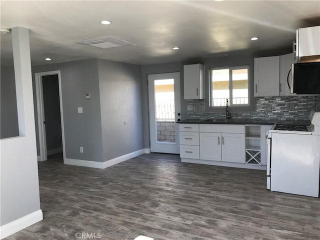 kitchen featuring tasteful backsplash, dark wood finished floors, dark countertops, white range, and a sink