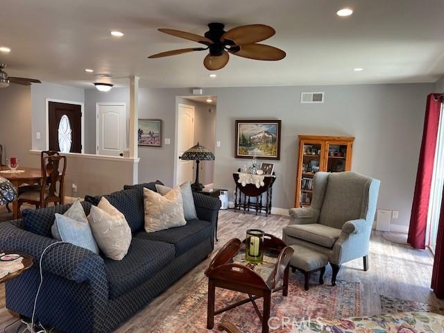 living area with a ceiling fan, recessed lighting, visible vents, and wood finished floors