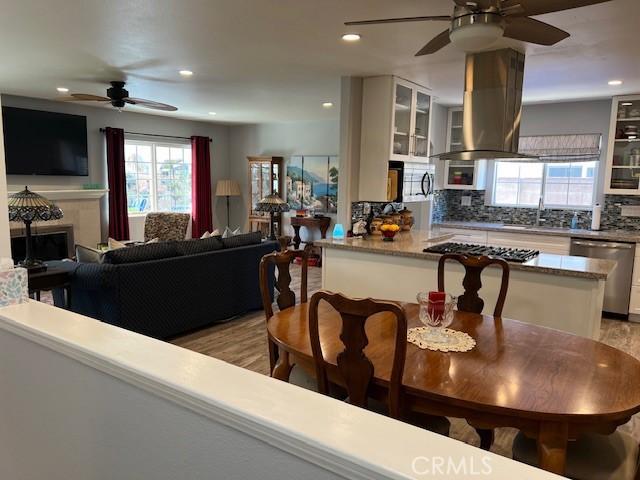 kitchen featuring island exhaust hood, white cabinetry, stainless steel appliances, and backsplash