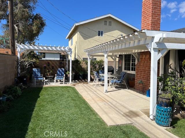 back of house featuring a lawn, a patio area, fence, and a pergola