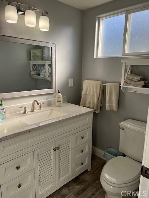 bathroom featuring baseboards, vanity, toilet, and wood finished floors