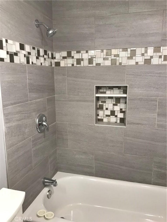 bathroom featuring washtub / shower combination and toilet