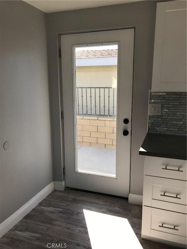 doorway to outside featuring dark wood-style flooring and baseboards