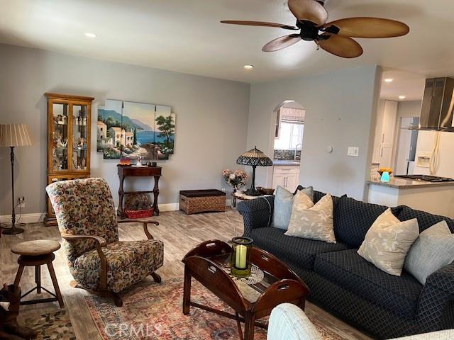 living area with baseboards, arched walkways, a ceiling fan, wood finished floors, and recessed lighting